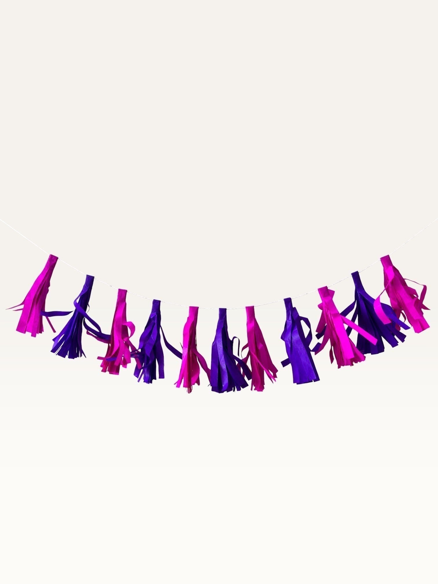 Paper Party Studio handmade tissue paper tassel garland in vibrant pink and purple for party decor and backdrops.
