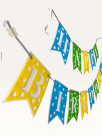 Paper Party Studio Happy Birthday banner with blue, green, and yellow polka dot swallowtail flags and white letters.