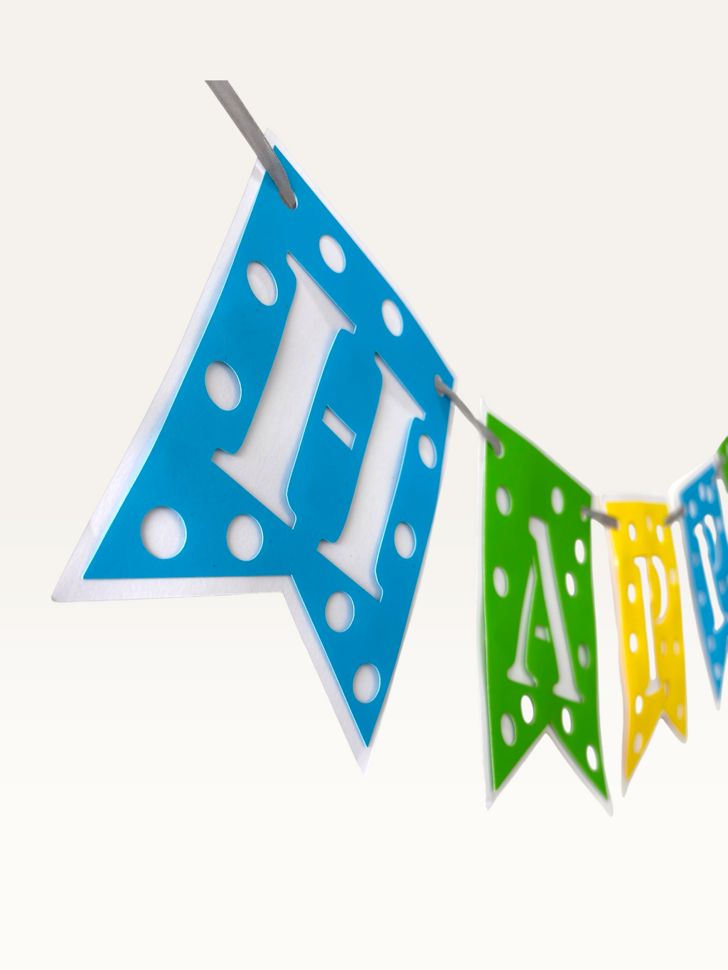 Paper Party Studio Happy Birthday banner with blue, green, and yellow swallowtail flags featuring white polka dots.