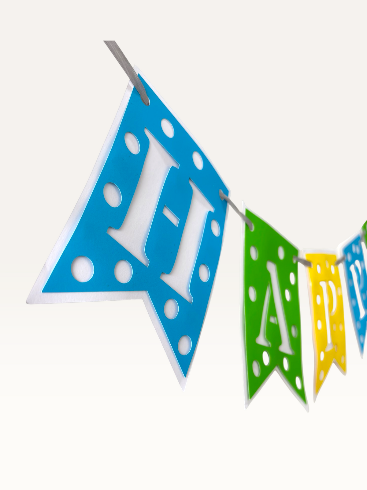 Paper Party Studio Happy Birthday banner with blue, green, and yellow swallowtail flags featuring white polka dots.