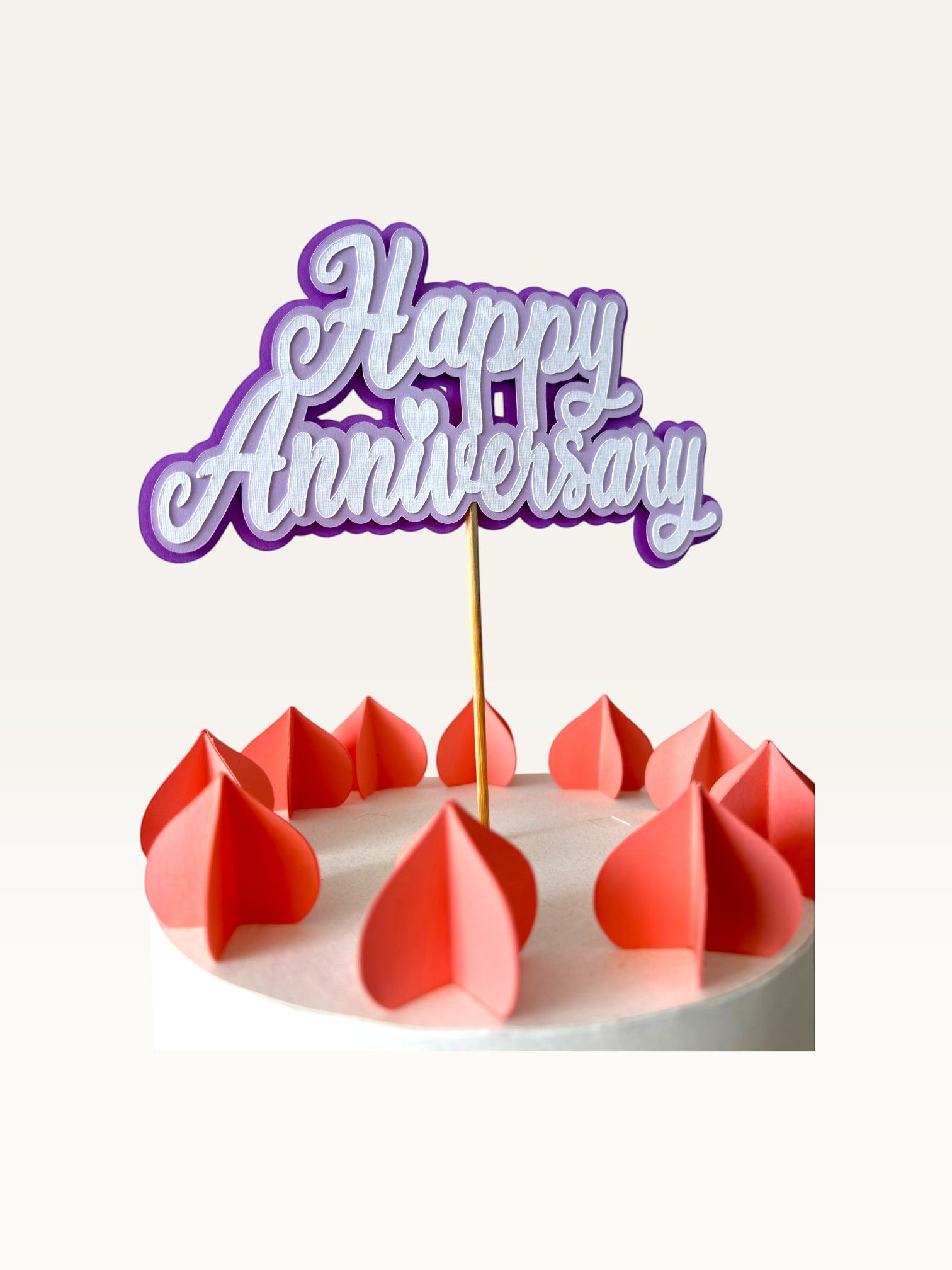 Paper Party Studio purple and white layered script Happy Anniversary cake topper with heart detail on a wooden pick.