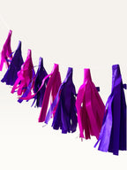 Paper Party Studio handmade tissue paper tassel garland in vibrant purple and hot pink for party decor.