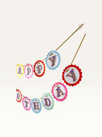 Paper Party Studio Happy Birthday banner with rainbow scalloped cardstock circles and ornate purple and gold letters.