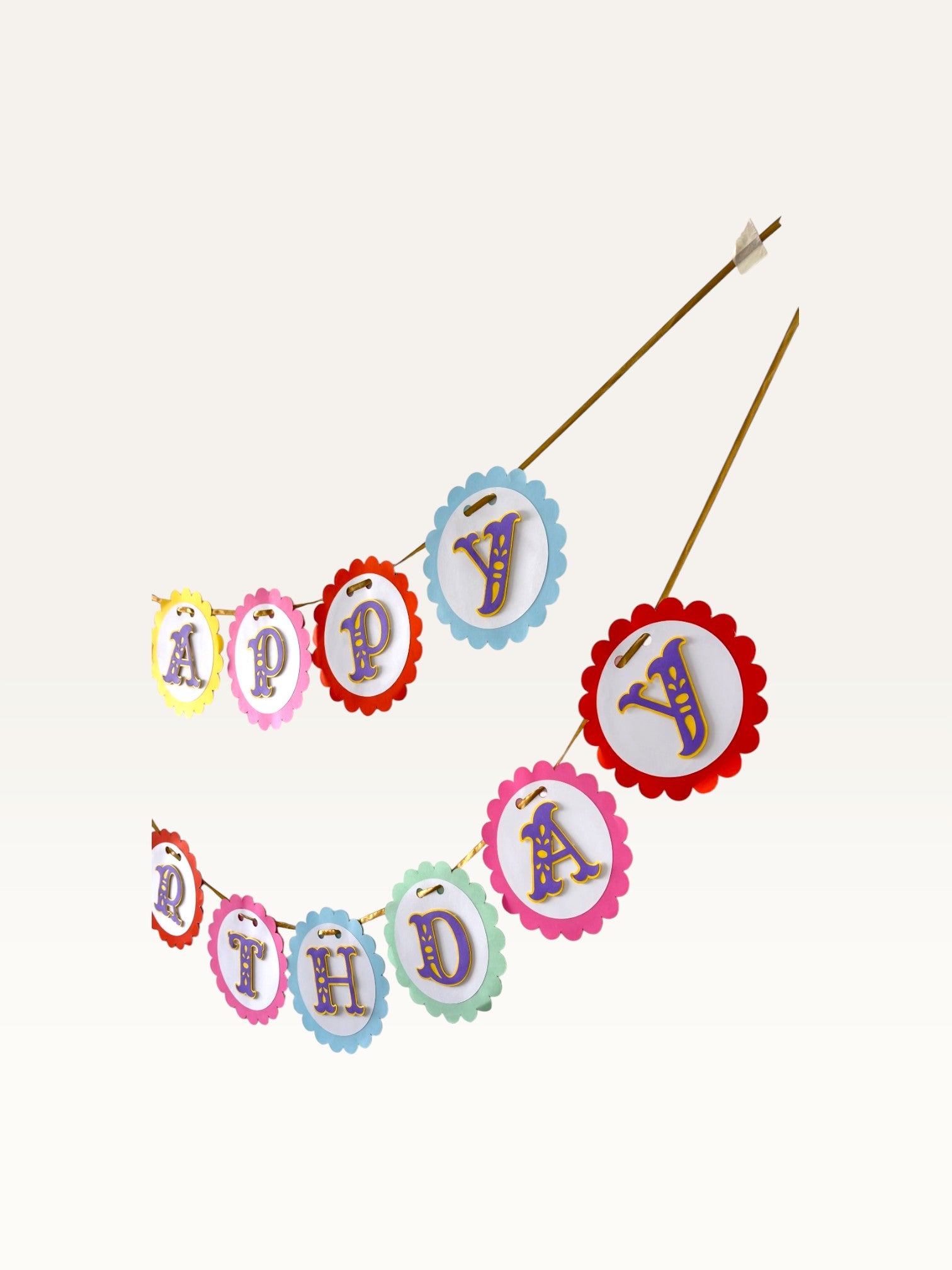 Paper Party Studio Happy Birthday banner with rainbow scalloped cardstock circles and ornate purple and gold letters.
