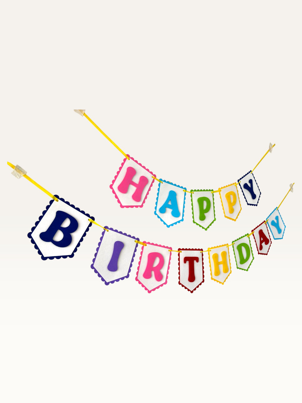 Paper Party Studio rainbow Happy Birthday banner with scalloped white paper flags and bold letters on a yellow cord.