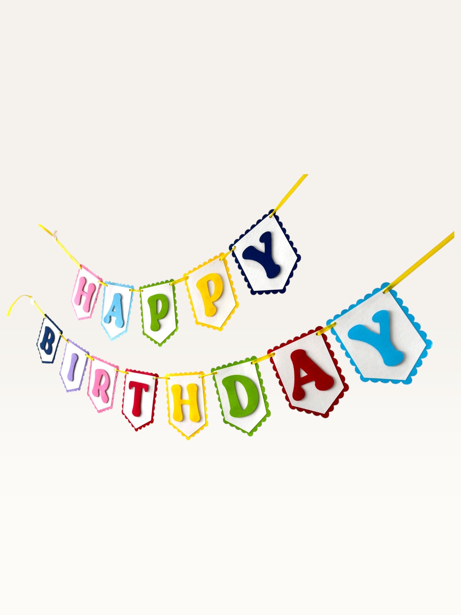 Paper Party Studio rainbow Happy Birthday banner with scalloped white paper flags on a yellow cord.