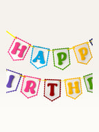 Paper Party Studio rainbow Happy Birthday banner with scalloped white paper flags on a bright yellow cord.