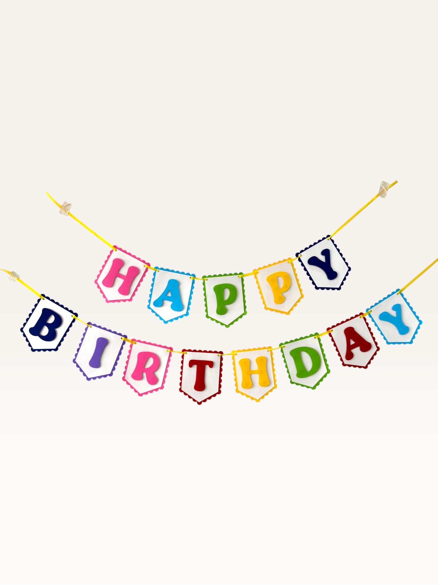 Paper Party Studio rainbow Happy Birthday banner with scalloped white paper flags on a bright yellow cord.