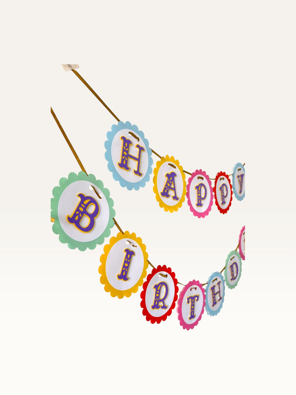 Paper Party Studio rainbow scalloped Happy Birthday banner with purple and gold ornate lettering on a gold ribbon.