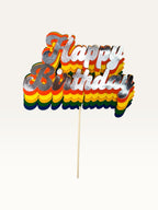 Paper Party Studio retro rainbow Happy Birthday cake topper with layered script lettering and silver foil finish.