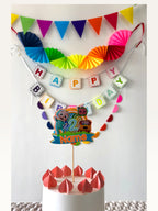 Paper Party Studio rainbow birthday decoration set with Cocomelon cake topper, paper fans, bunting, and banner.