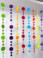 Paper Party Studio rainbow circle garland with graduated paper dots in bright colours, strung on white thread.