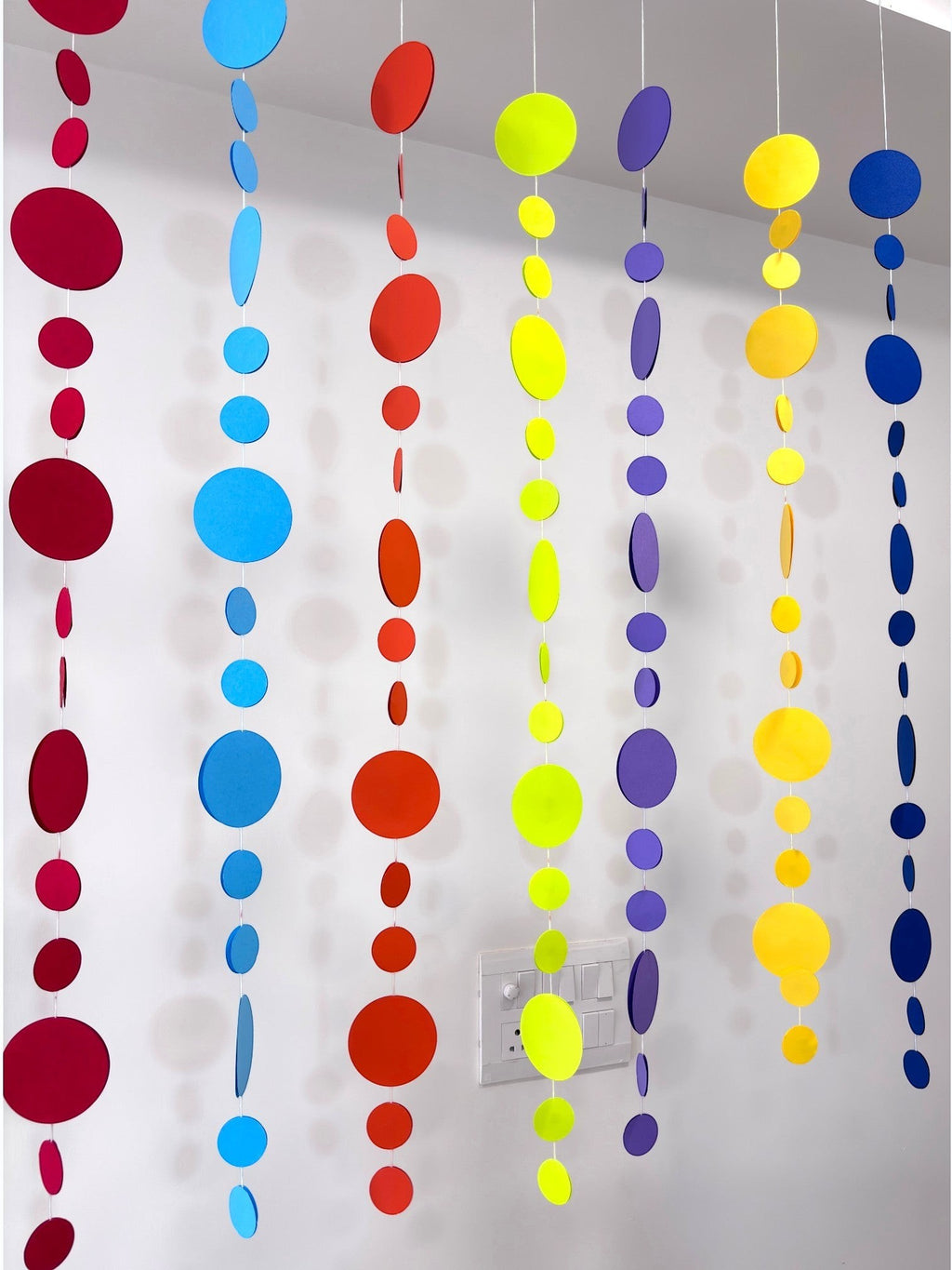 Paper Party Studio rainbow circle garland with graduated paper dots in red, blue, orange, yellow, green, and purple.