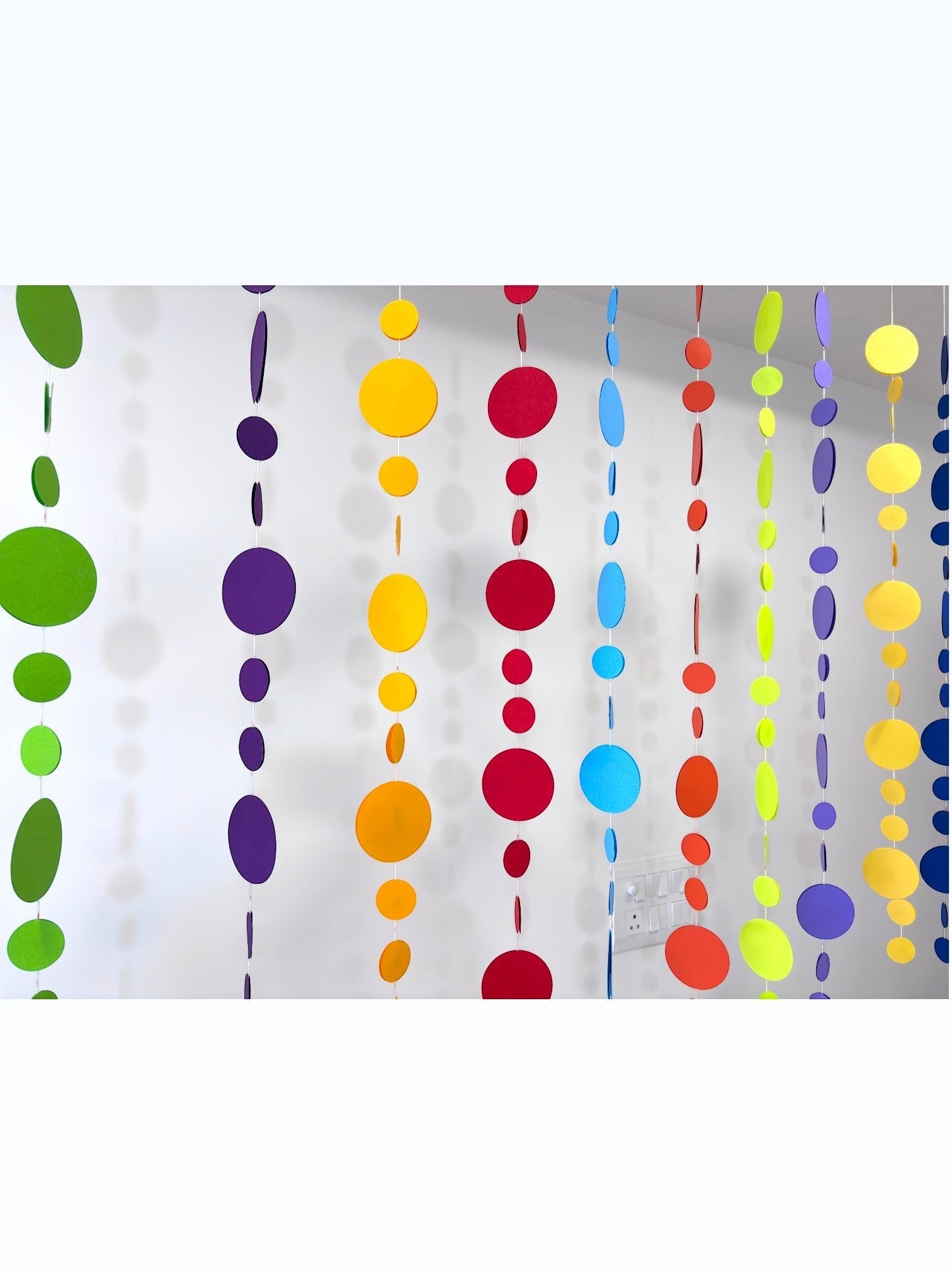 Paper Party Studio rainbow circle garland with graduated paper dots in red, orange, yellow, green, blue, and purple.