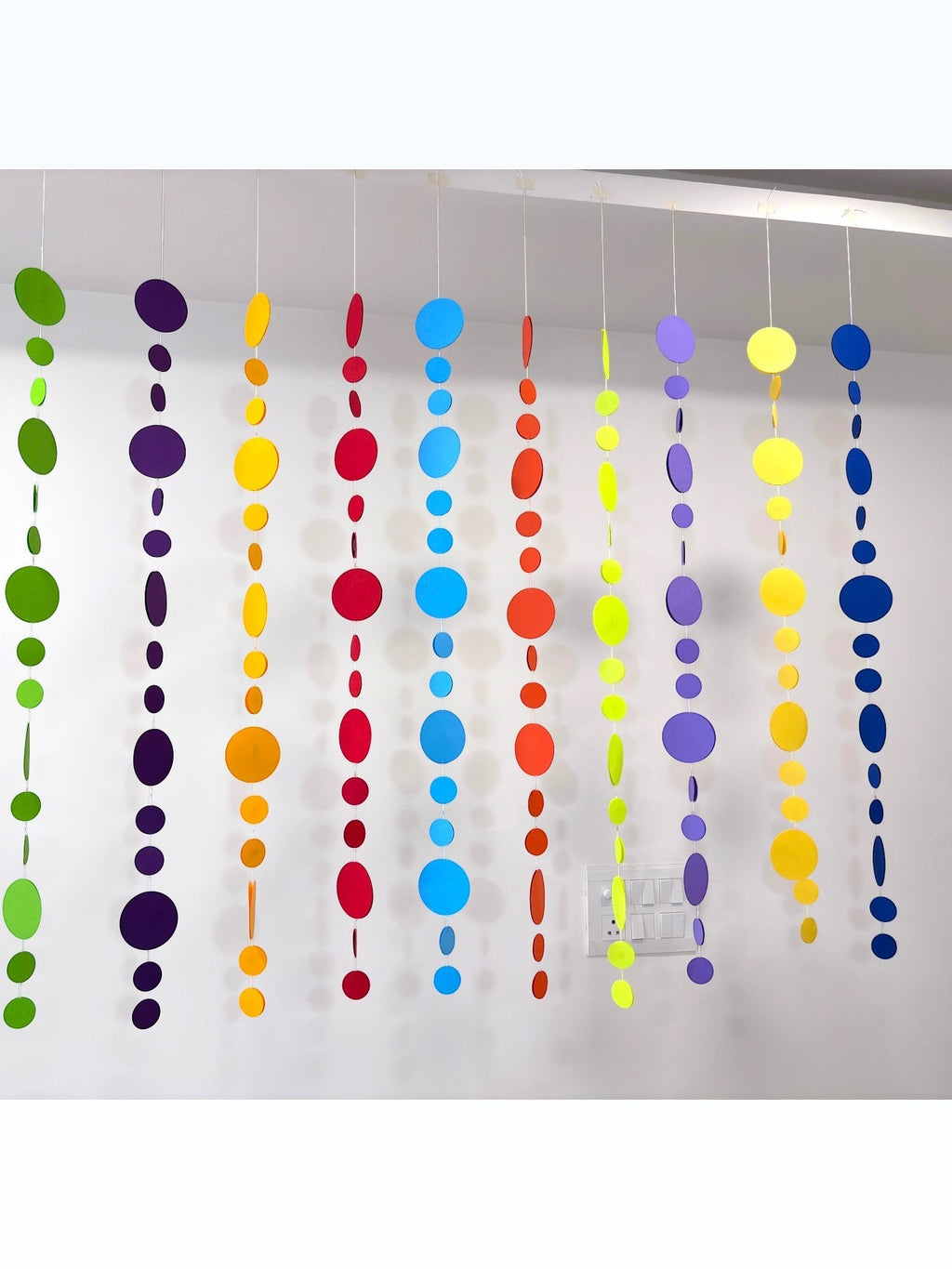 Paper Party Studio rainbow circle garland with 10 strings of graduated paper dots in vibrant colors, perfect for parties and backdrops.