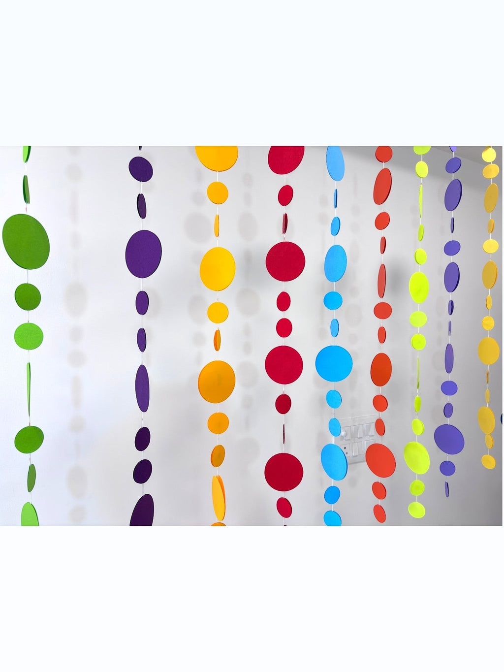 Paper Party Studio rainbow circle garland with graduated sizes and bright tones, perfect for parties and backdrops.