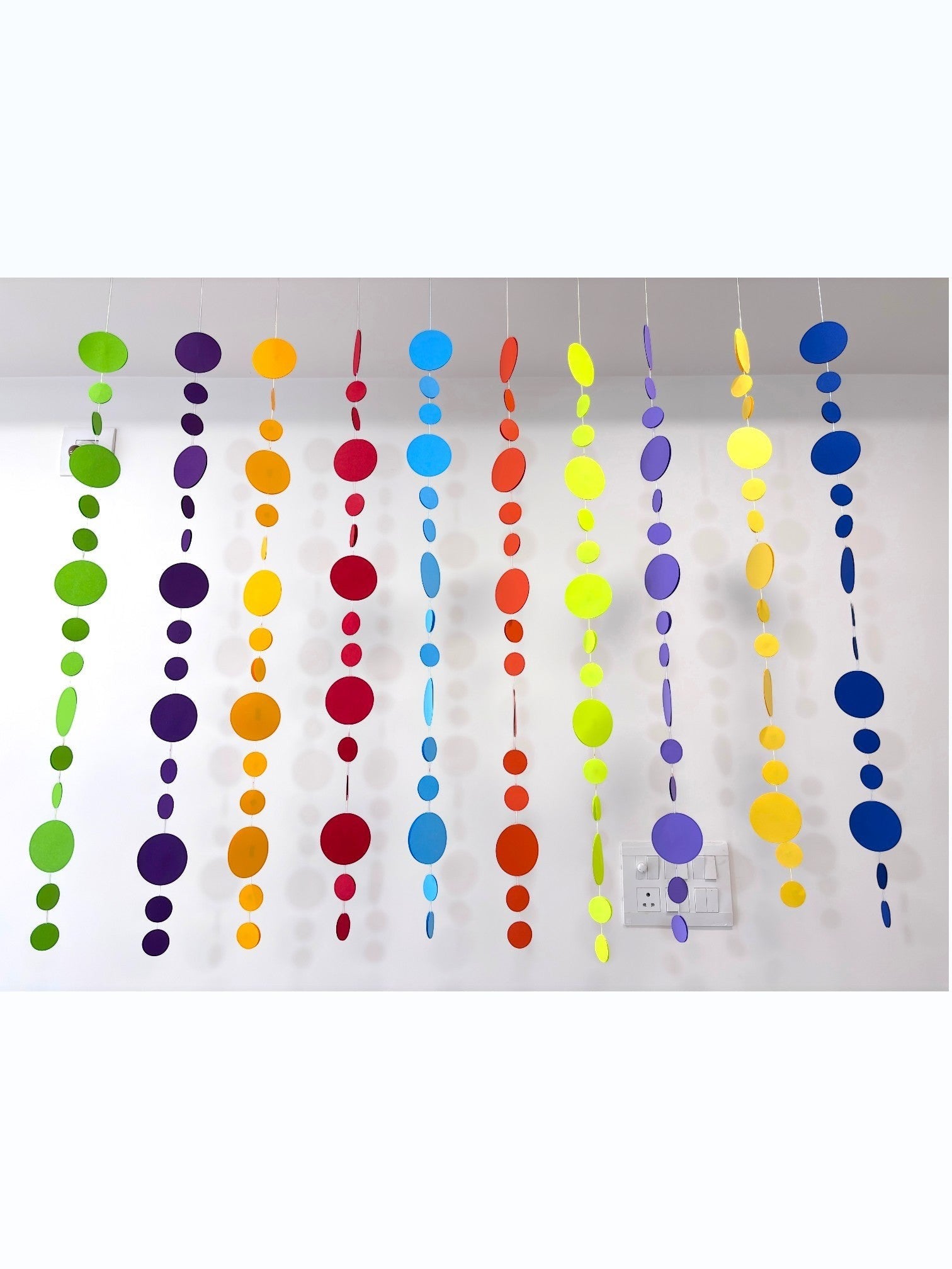 Paper Party Studio rainbow circle garland with 10 strings of graduated paper dots in vibrant colors, perfect for parties and backdrops.