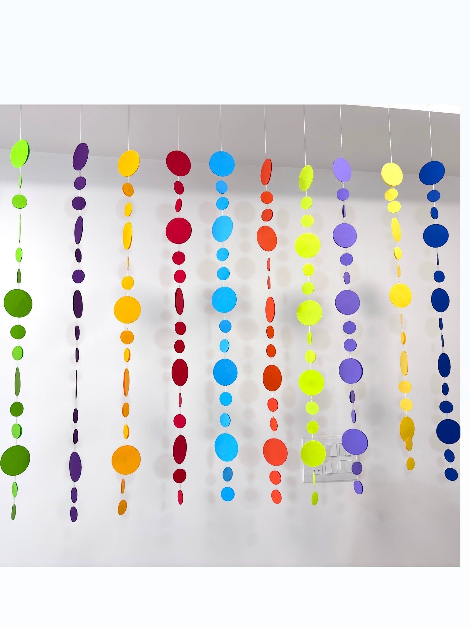 Paper Party Studio rainbow circle garland with 10 strings of graduated paper dots in vibrant colors, perfect for parties.