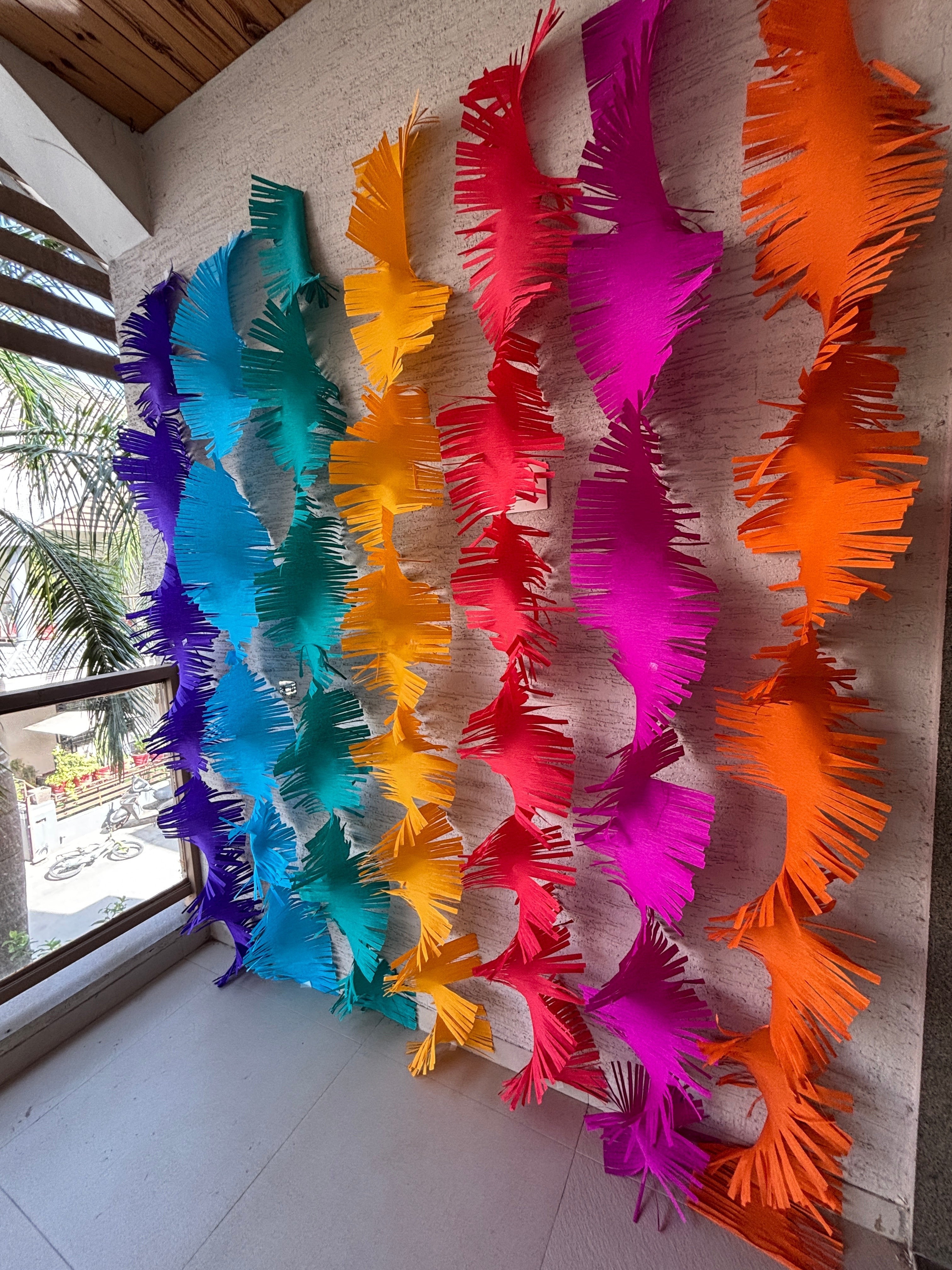 Paper Party Studio rainbow fringe streamers made of crepe paper, perfect for backdrops and parties.