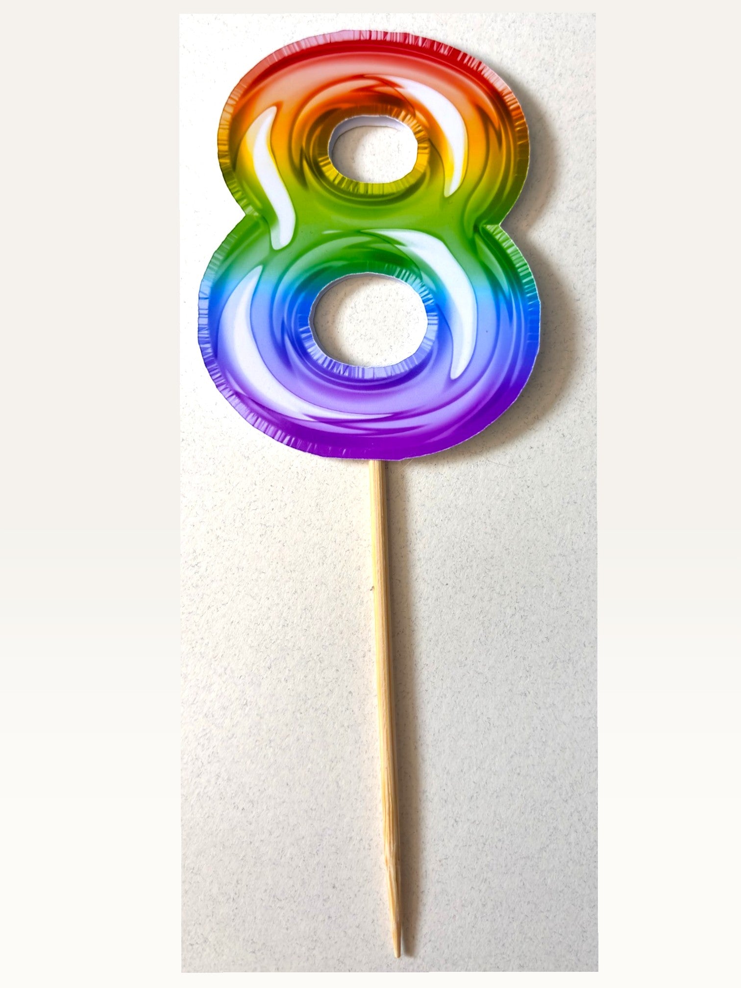 Paper Party Studio rainbow foil number 8 cake topper on a bamboo stick with a vibrant gradient finish.