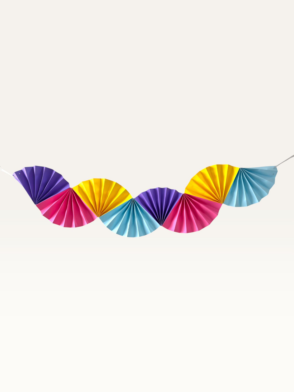 Paper Party Studio rainbow paper fan garland featuring vibrant purple, yellow, pink, and blue folded scalloped fans.
