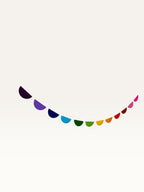 Paper Party Studio rainbow scallop garland featuring colourful paper half-circles on a string for party decoration.