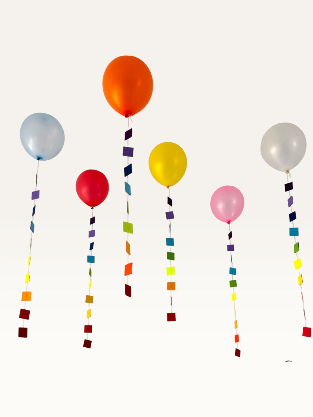 Paper Party Studio rainbow square garland strings hanging as colorful balloon tails for party decoration