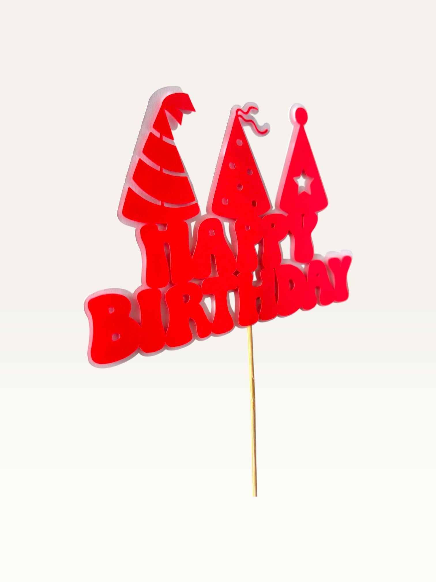 Paper Party Studio red Happy Birthday cake topper with three party hat cut-outs on a wooden pick.