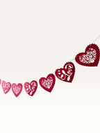 Paper Party Studio red heart bunting with scalloped edges, floral cut-outs, and cursive Love text for romantic decor.