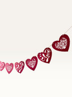Paper Party Studio red heart bunting with scalloped edges, floral cut-outs, and cursive Love script for romantic decor.