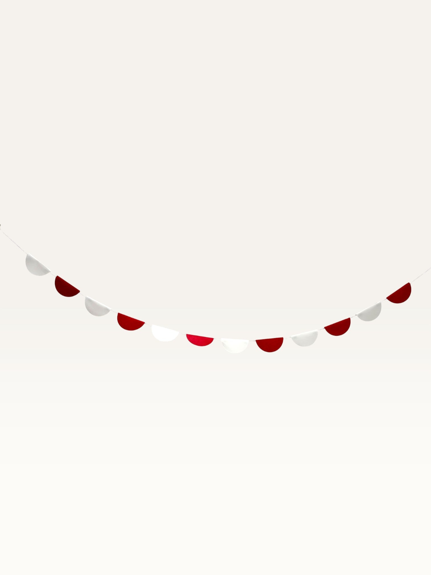 Paper Party Studio red and white paper scallop garland hanging against a plain background