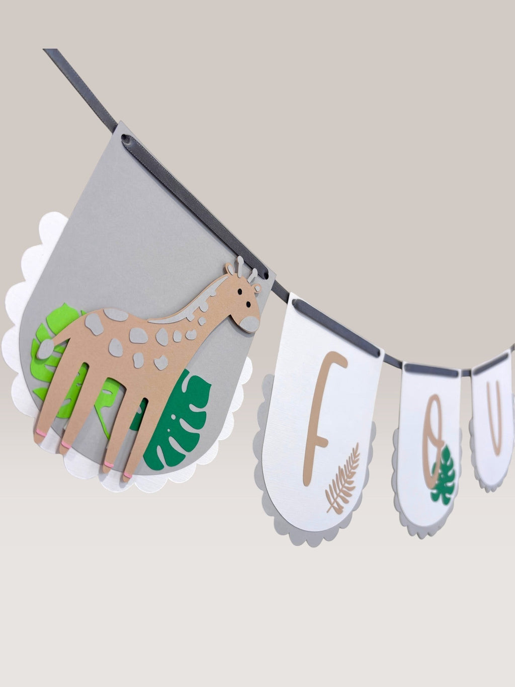 Paper Party Studio safari birthday banner with grey scalloped flags, giraffe, tiger, and kraft lettering spelling "FOUR".