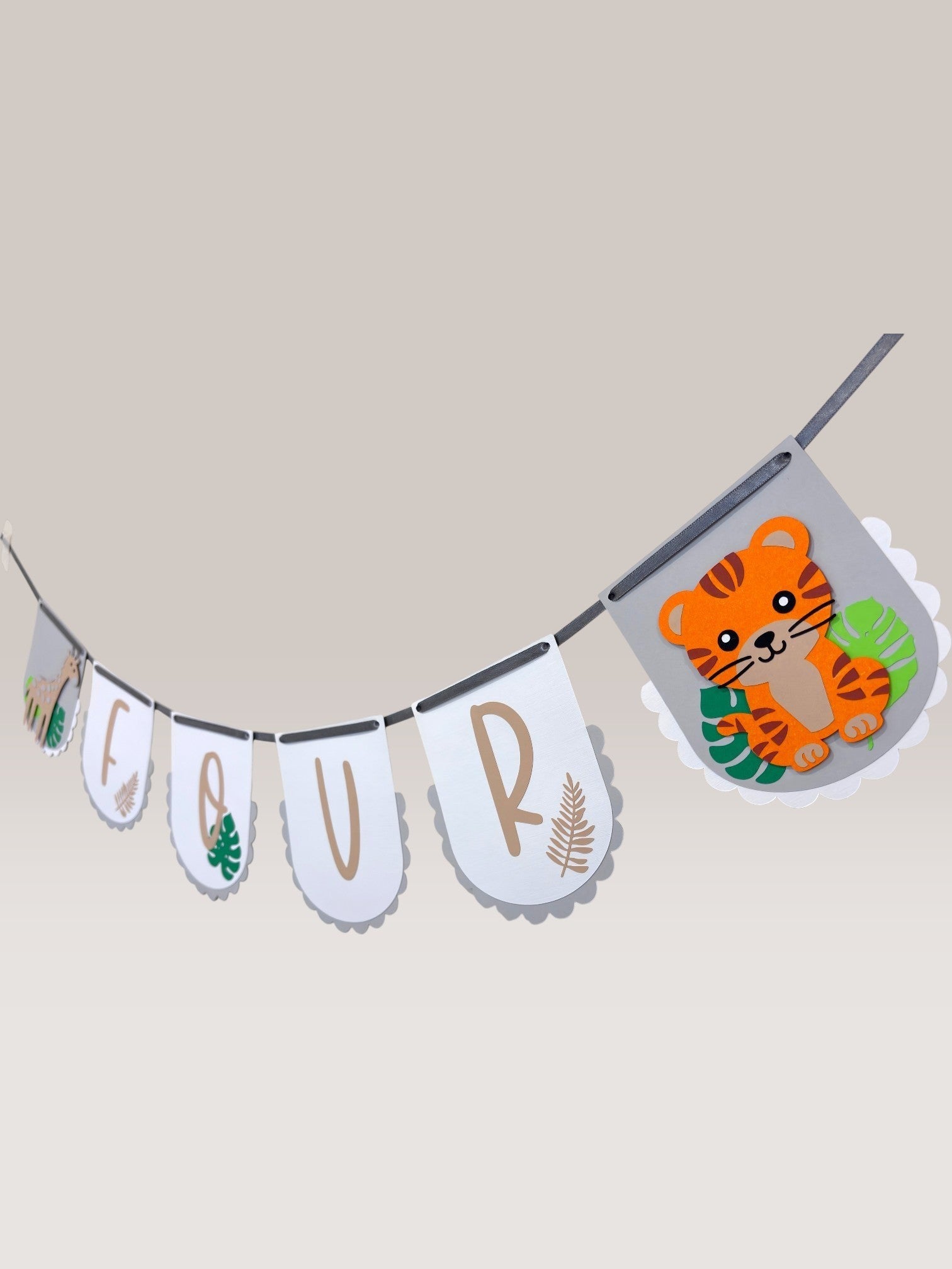 Paper Party Studio safari birthday banner with white scalloped flags spelling "FOUR", featuring a giraffe, tiger, and tropical leaves.