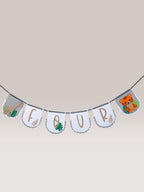 Paper Party Studio safari birthday banner with white scalloped flags spelling "FOUR", featuring a giraffe and tiger with tropical leaves.
