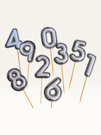 Paper Party Studio silver foil number cake toppers with chrome finish on bamboo sticks for birthday celebrations.