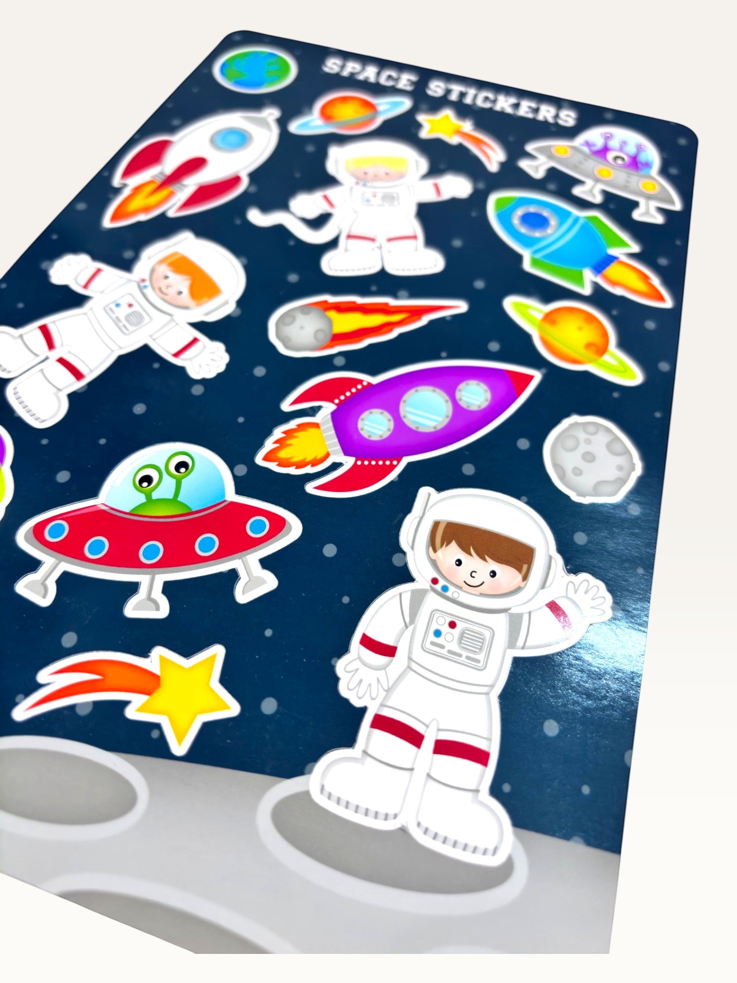Paper Party Studio glossy sticker sheet featuring colorful rockets, astronauts, and aliens on a starry blue background.