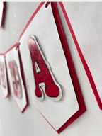 Paper Party Studio red and white swallowtail birthday banner with black spider-web letter detailing