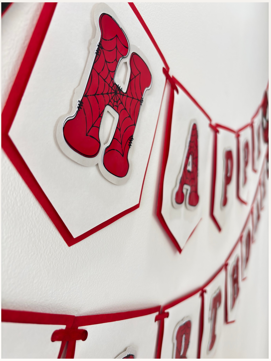 Paper Party Studio red and white swallowtail Happy Birthday banner with black spider-web detailing on each letter