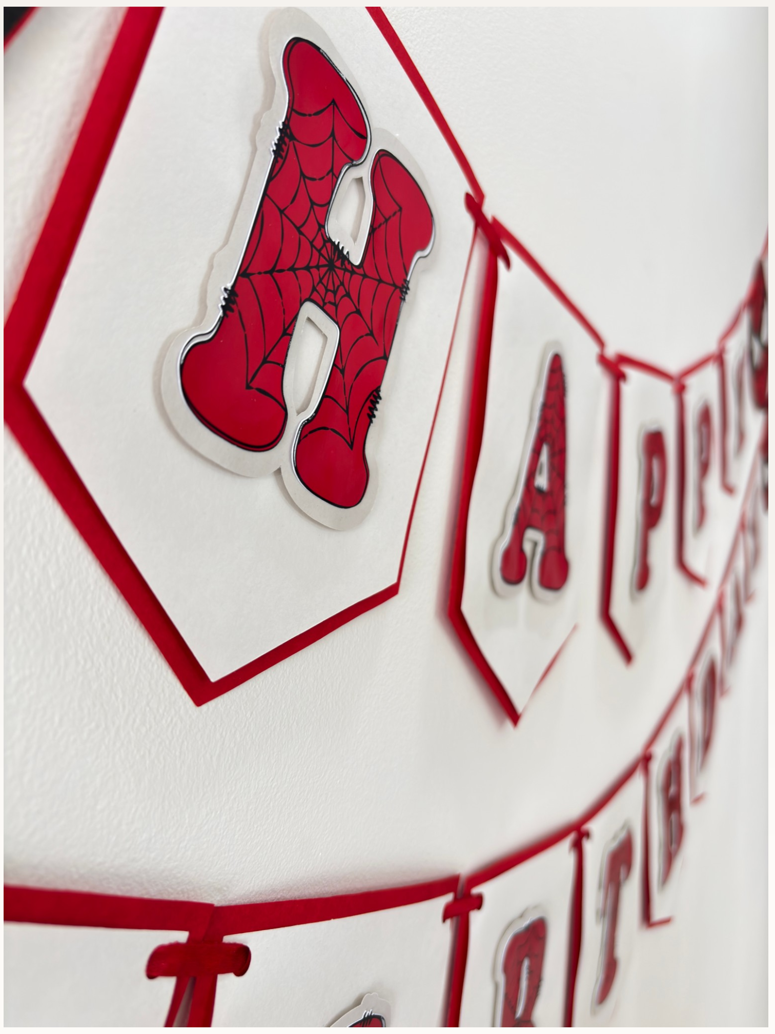 Paper Party Studio red and white swallowtail Happy Birthday banner with black spider-web detailing on each letter