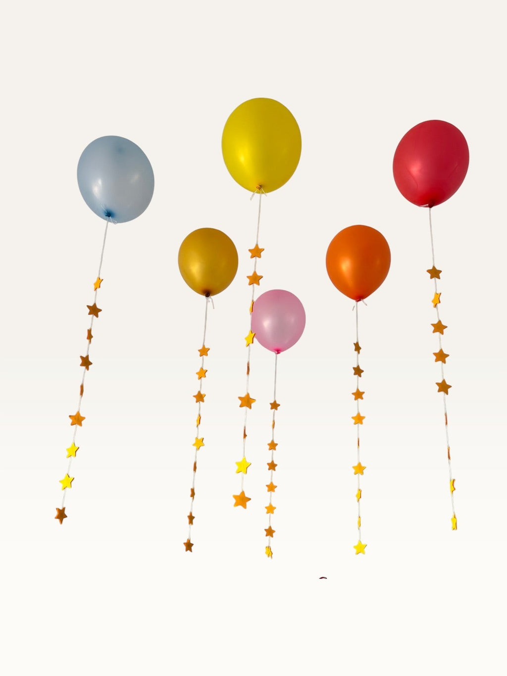 Paper Party Studio set of 10 yellow and dark yellow paper star garland strings attached to colorful party balloons.