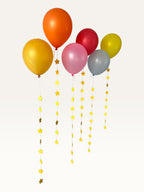 Paper Party Studio set of 10 yellow paper star garland strings hanging from colorful party balloons