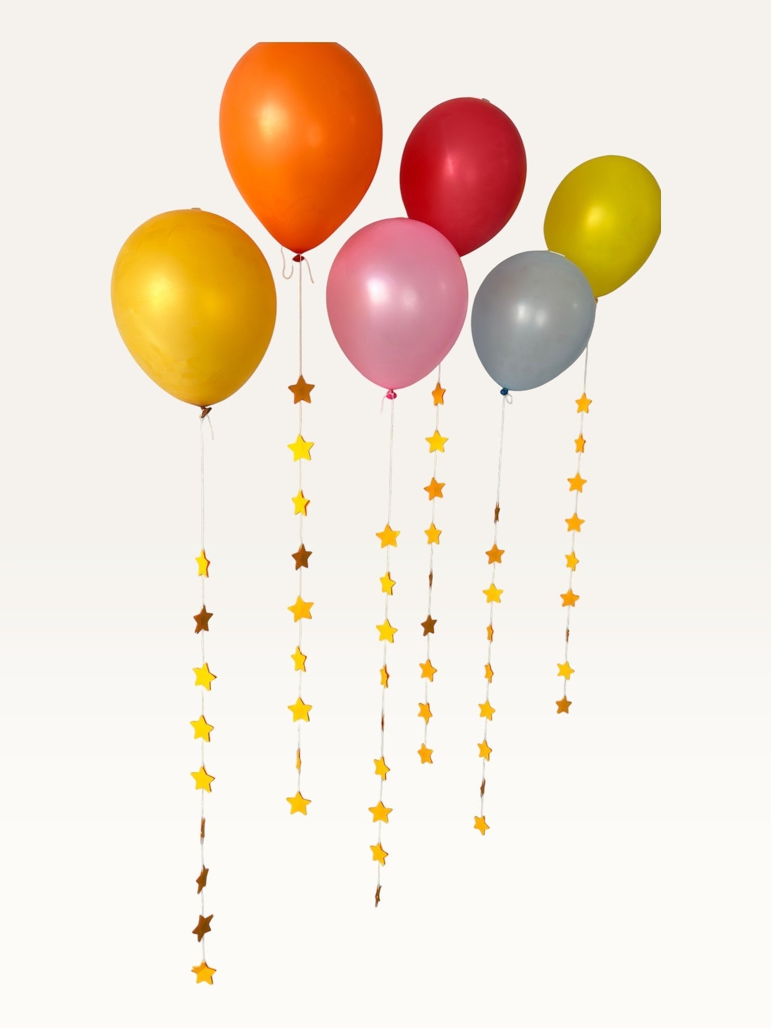 Paper Party Studio set of 10 yellow paper star garland strings hanging as decorative balloon tails for celebrations.