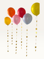 Paper Party Studio set of 10 yellow paper star garland strings hanging from colorful party balloons