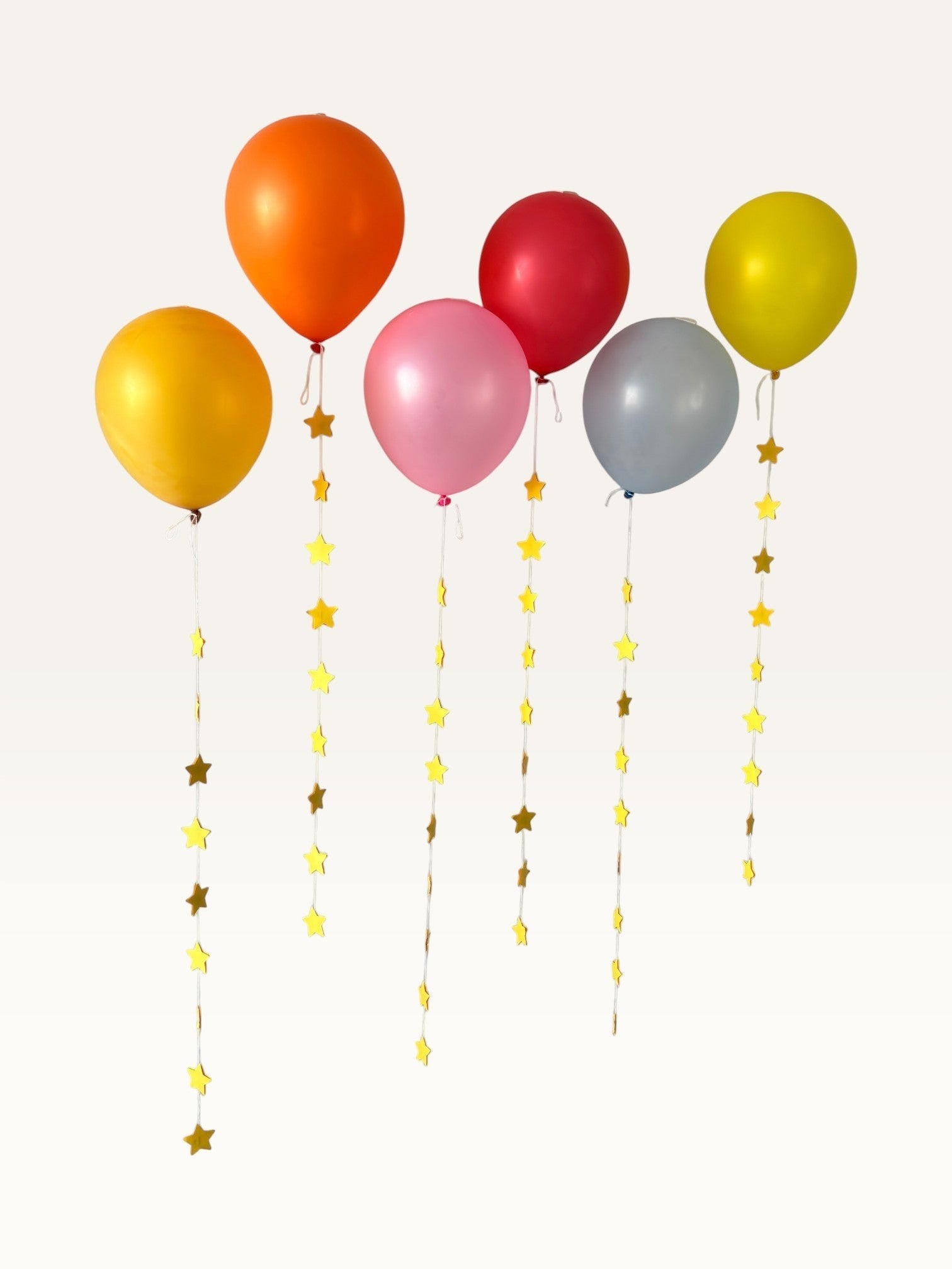 Paper Party Studio set of 10 yellow paper star garland strings hanging from colorful party balloons