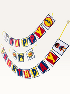 Paper Party Studio superhero birthday banner with red, blue, and yellow comic burst flags and masked hero characters.