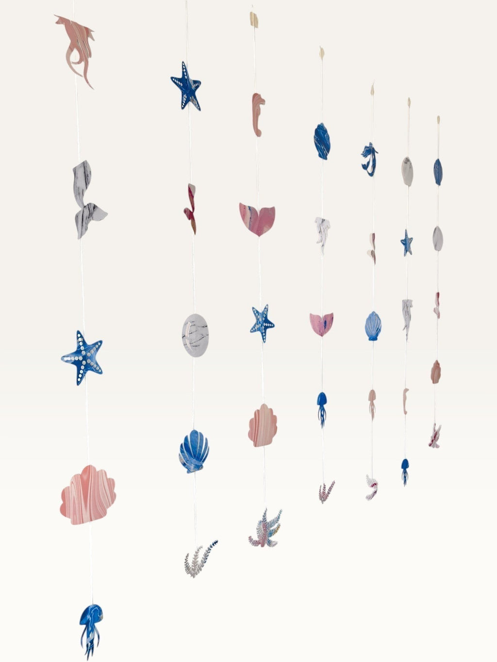 Paper Party Studio under the sea hanging backdrop with pink and blue cardstock mermaid, shell, and starfish cutouts.