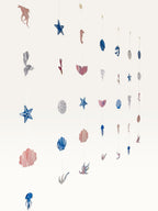 Paper Party Studio under the sea hanging backdrop with pink and blue cardstock mermaid, shell, and starfish cutouts.