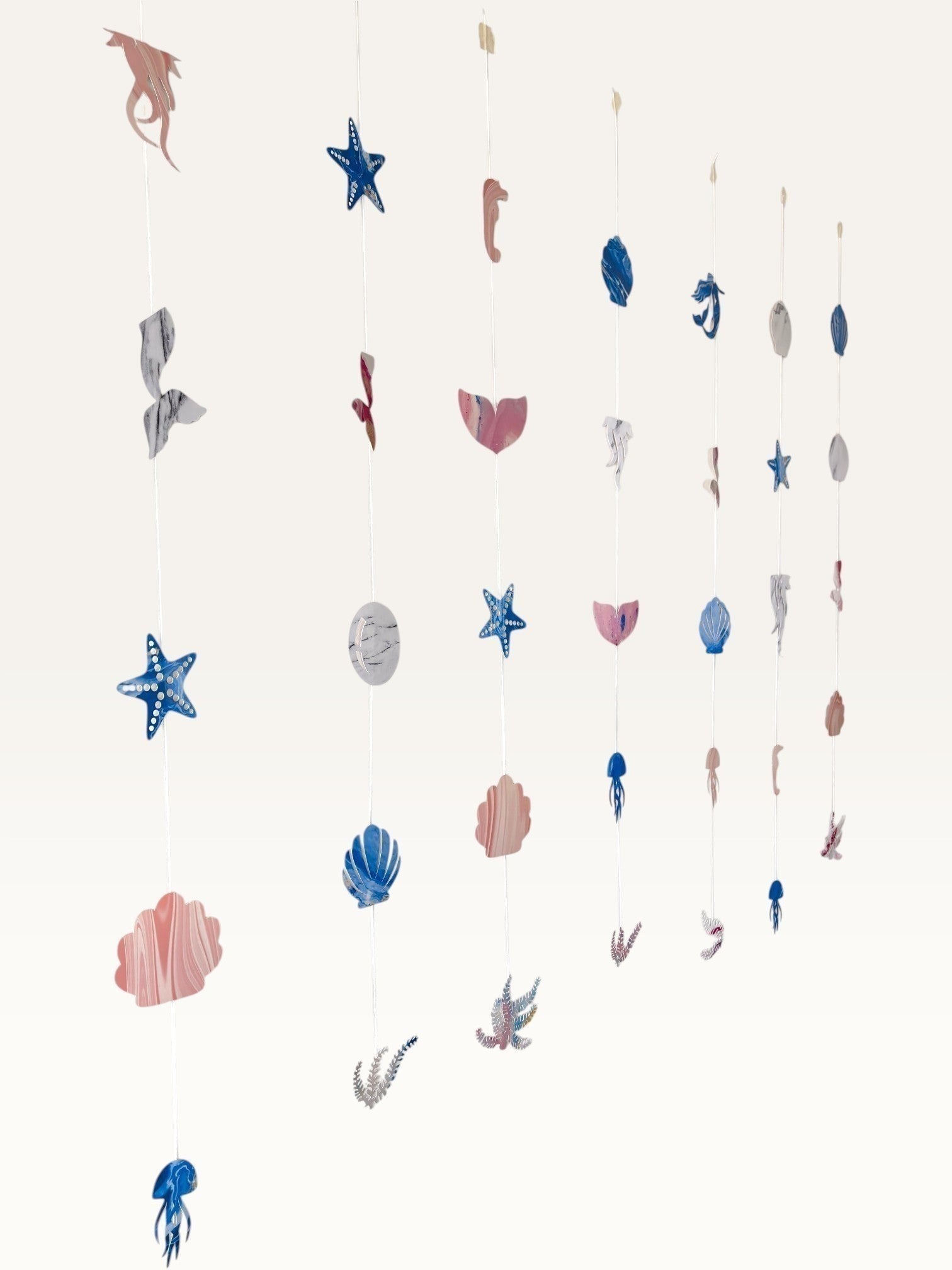 Paper Party Studio under the sea hanging backdrop with pink and blue cardstock mermaid, shell, and starfish cutouts.