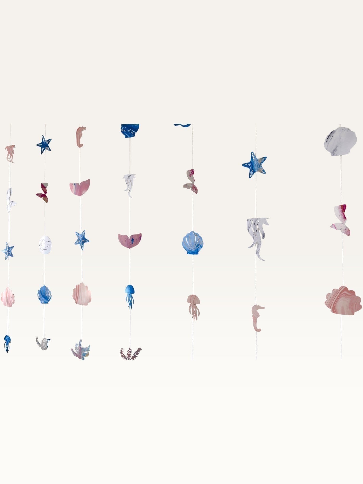 Paper Party Studio under the sea backdrop with hanging strings of cardstock shells, starfish, and mermaid tails.
