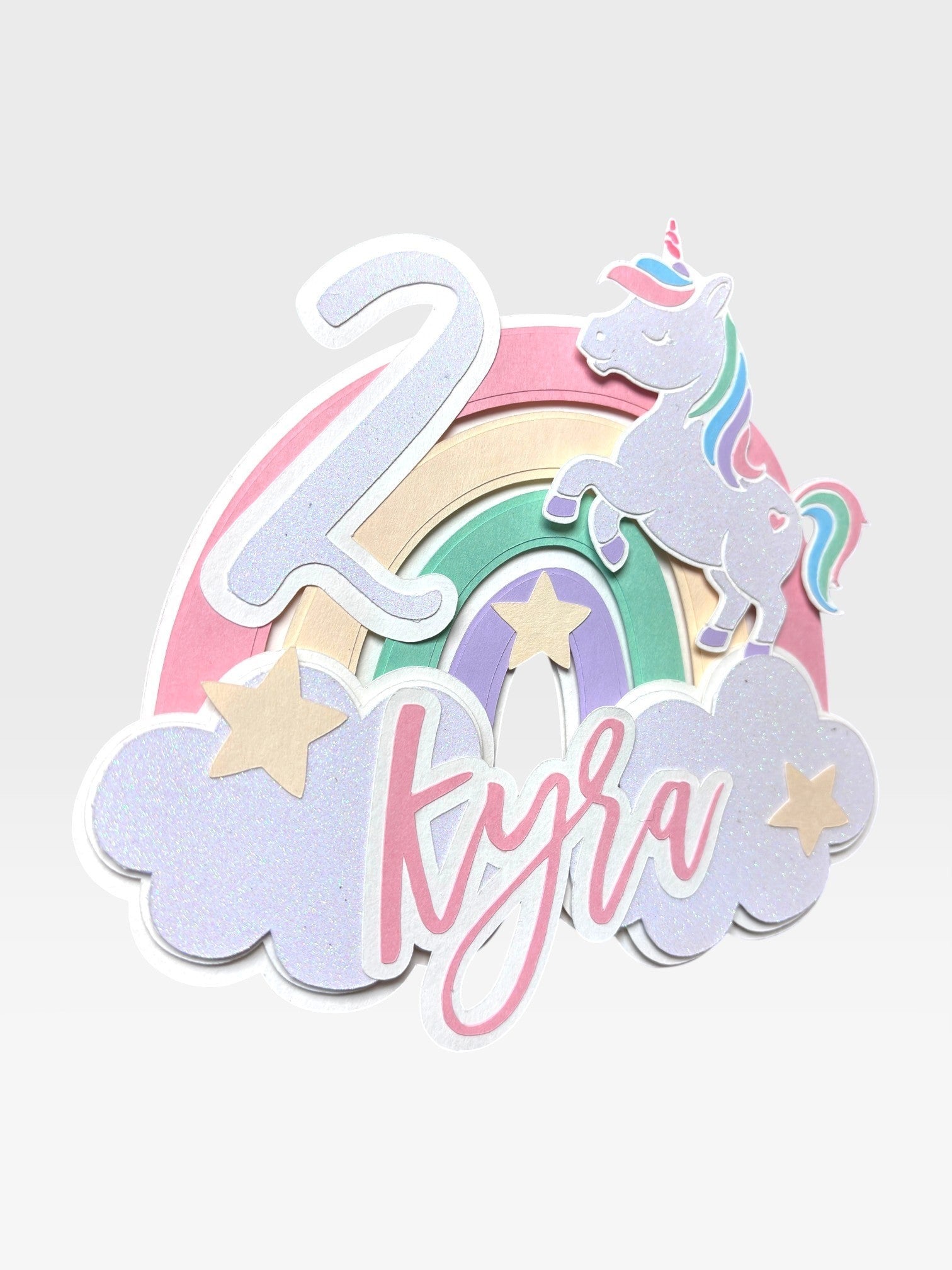 Paper Party Studio personalised unicorn cake topper with pastel rainbow, clouds, custom name and age.